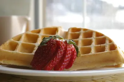 a waffle with a strawberry on a white plate at Country Encounters Accommodations in Coleman