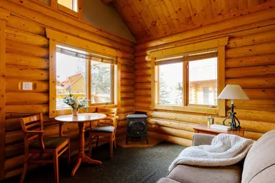a living room with a table in a log cabin at Miette Mountain Cabins in Jasper