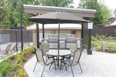a table and chairs under an umbrella on a patio at Lake Placid Lodge by Whistler Retreats in Whistler