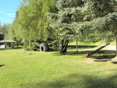 a park with a tree and a bench in the grass at Rivermount Motel in Little Fort