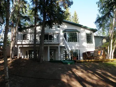 a white house with trees in front of it at Great Slave Lakeside Bed & Breakfast in Yellowknife