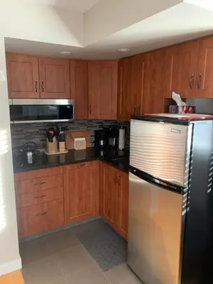 a kitchen with wooden cabinets and a stainless steel refrigerator at Dragonfly Inn Loft Suite in Sherwood Park