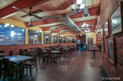 a restaurant with tables and chairs and a brick wall at Grizz Hotel in Revelstoke