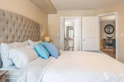 a bedroom with a large white bed with blue pillows at Rustic Modern 2 Bed 2 Bath with Lakeview Pool and Hot Tub in Invermere