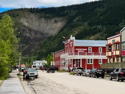 a street with cars parked in front of a red building at The Downtown, a Coast Hotel in Dawson City