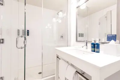 a white bathroom with a shower and a sink at Four Points by Sheraton Kelowna Airport in Kelowna