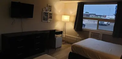 a bedroom with a bed and a dresser and a window at New Frontier Hotel in Coronation
