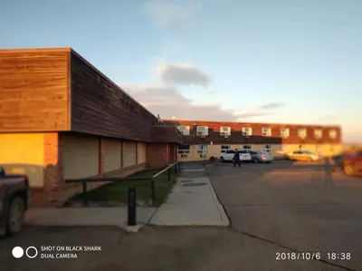 a building in a parking lot with a person walking past it at New Frontier Hotel in Coronation