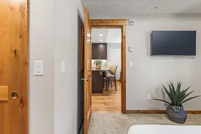 a hallway with a door leading into a room with a television at Spring Creek Luxury King One Bedroom at White Spruce Lodge in Canmore