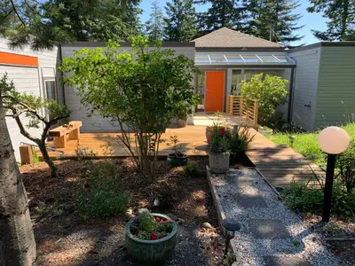 a backyard with a house with a tree and plants at Forest by the Sea Rentals in Merville