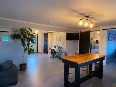 a living room with a wooden table and a dining room at Sunrise Cabin secluded beach front accommodation in Sandspit