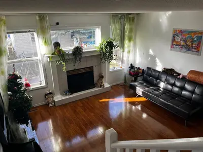 a living room with a black leather couch and a fireplace at Hidden valley treehouse home! in Calgary