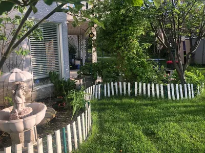 a white picket fence with a fountain in a yard at Hamptons Rose garden family! in Calgary
