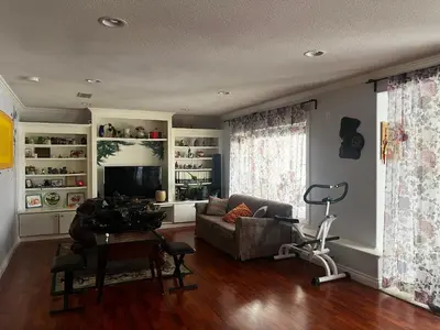 a living room with a couch and a television at Hamptons Rose garden family! in Calgary