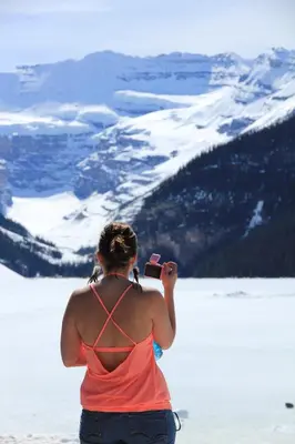 a woman taking a picture of a snow covered mountain at Mountain View Escape - Copperstone 2BR & Hot Tub in Canmore