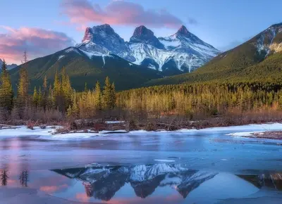 a mountain reflection in the water with a river at Mountain View Escape - Copperstone 2BR & Hot Tub in Canmore