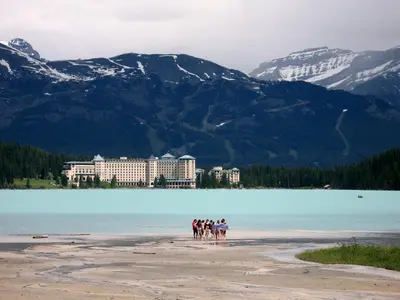 a group of people riding horses on a beach near a lake at WindTower Resort - 1 Bed Hotel Room 166 in Canmore
