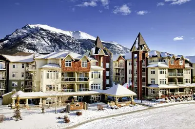 a resort in the snow with a mountain in the background at Anniversary and Honeymoon 1 Bedroom Suite 168 in Canmore