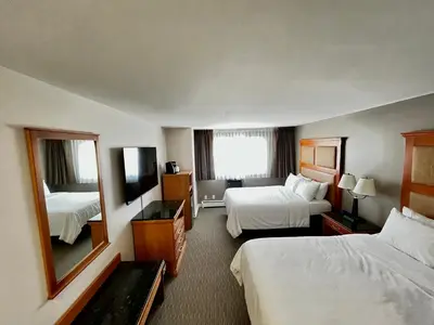 a hotel room with two beds and a mirror at Anavada Inn & Suites - Prince George in Prince George
