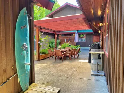 a patio with a table and chairs and a surfboard at Whalers Guesthouse in Tofino