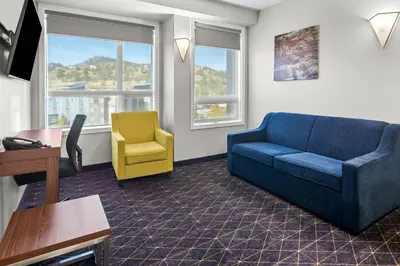 a living room with a blue couch and a yellow chair at Park Inn by Radisson, Kelowna in Kelowna