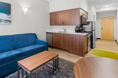 a living room with a blue couch and a kitchen at Park Inn by Radisson, Kelowna in Kelowna