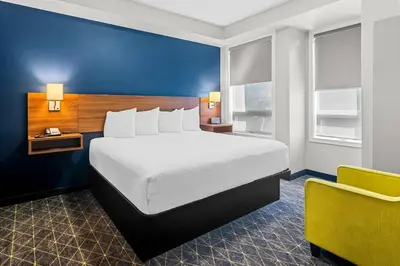 a hotel room with a bed and a yellow chair at Park Inn by Radisson, Kelowna in Kelowna