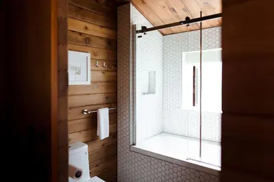 a bathroom with a shower and a toilet and a window at Bodega Ridge & Cove Cabins in Fernwood