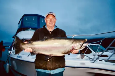 a man holding a fish in front of a boat at Kootenay Wild Guest Suites in Nelson