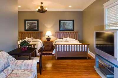 a living room with two beds and a tv at Kootenay Wild Guest Suites in Nelson