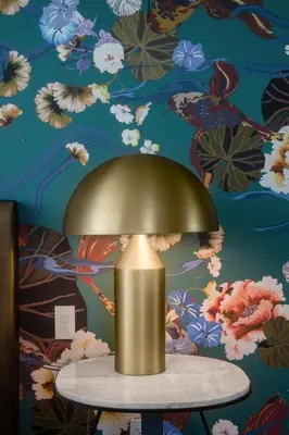 a gold lamp on a table in front of a floral wall at Versante Hotel in Richmond