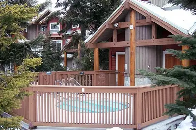 a house with a wooden fence and a pool at Symphony by Whistler Premier in Whistler