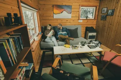 a man and a woman sitting on a couch in a room at Little Atlin Lodge in Tagish