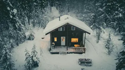 a small cabin with snow on the roof at Little Atlin Lodge in Tagish