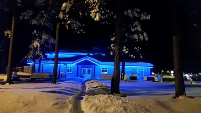 a blue building with snow in front of it at night at Rocky Inn in Valemount