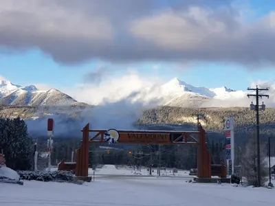 a sign in the snow with mountains in the background at Rocky Inn in Valemount