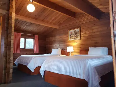 a bedroom with two beds in a log cabin at Rocky Inn in Valemount