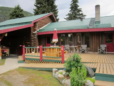 a log cabin with a deck and a patio at Summit River Lodge & Campsites in Valemount