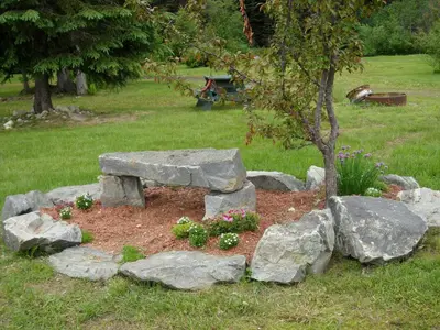 a stone bench in a garden with rocks at Summit River Lodge & Campsites in Valemount