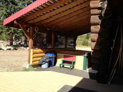 a wooden pavilion with a bench and a picnic table at Summit River Lodge & Campsites in Valemount