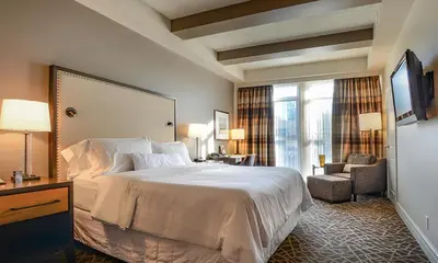 a hotel room with a large bed and a chair at Fairways Hotel on the Mountain in Victoria