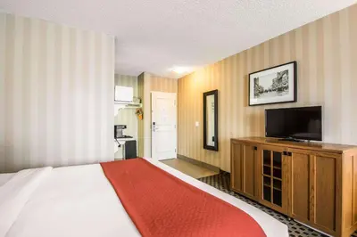a hotel room with a bed and a flat screen tv at Quality Hotel in Drumheller