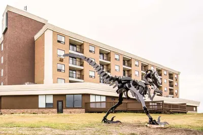a statue of a dinosaur in front of a building at Quality Hotel in Drumheller