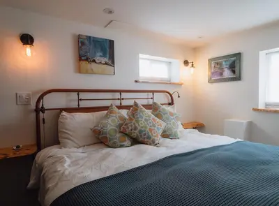 a bedroom with a bed with pillows on it at eARTh studios GallerySuite in Nelson