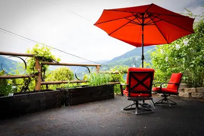 two chairs and a red umbrella on a patio at eARTh studios GallerySuite in Nelson