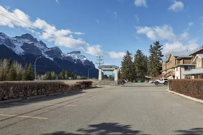 an empty street with mountains in the background at Mountain Gate - Pet Friendly 2BR w Mountain Views and open hot tub in Canmore
