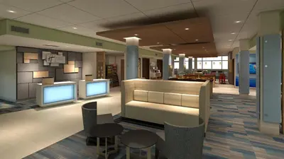 a lobby with two monitors and tables and chairs at Holiday Inn Express & Suites - Calgary Airport Trail NE by IHG in Calgary