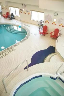 a swimming pool in a hospital room with red chairs at Gold Eagle Lodge in North Battleford