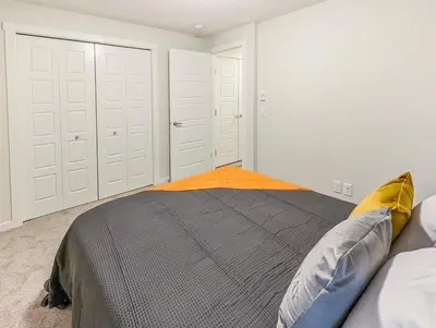 a bedroom with white doors and a bed with pillows at GlobalStay Cranbrook Townhome Suites in Calgary