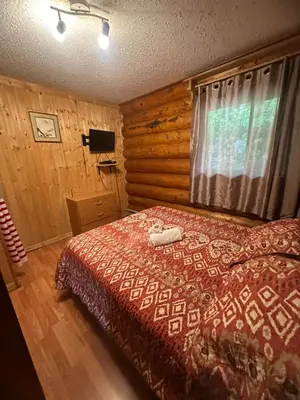 a bedroom with a bed in a log cabin at Lac Des Roches Resort in Bridge Lake